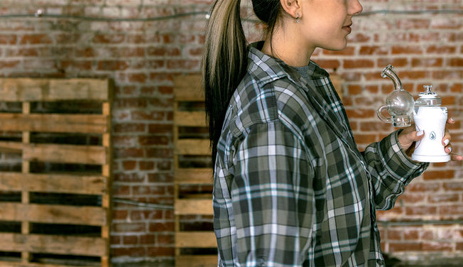 A person in a plaid shirt is holding a white electric dab rig by Dr.Dabber.